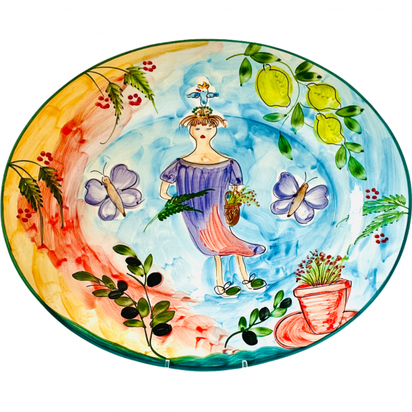 En underbart ovalt fat i Lena Linderholm serie Happy girl. Fatet är målat för hand och har en flicka i lila klänning med en fågel på huvudet. Fatet är färgrikt och har fjärilar blommor och citroner i glasyren. Bottenfärgen är ljusblå, röd och gul.