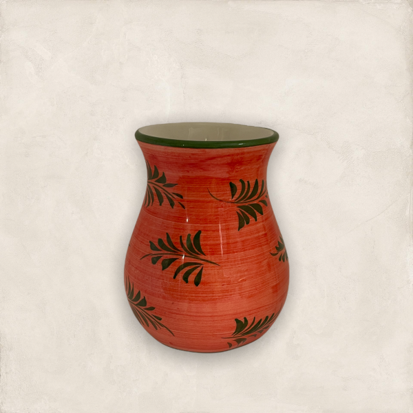 En lite rund vas i röda varma färger med gröna grankvistar målat på vasen. Vasen har en jättebra form.